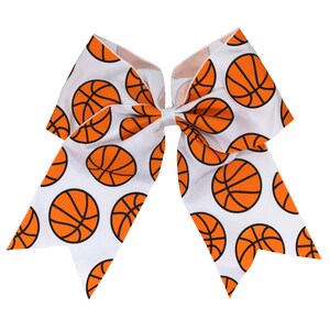 May include: White cheer bow with a basketball pattern. The bow is made of white ribbon with orange basketballs printed on it.