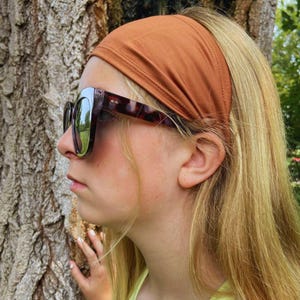 K&ouml;nnte beinhalten: Eine junge Person mit langen blonden Haaren, die ein braunes Stirnband und eine Schildpatt-Sonnenbrille tr&auml;gt.