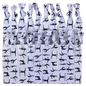 May include: A set of 24 purple and silver hair ties with a black silhouette of a gymnast on a bar repeated on each tie.