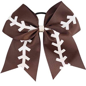 May include: A brown cheer bow with a white football stitch design. The bow is attached to a black elastic hair tie.