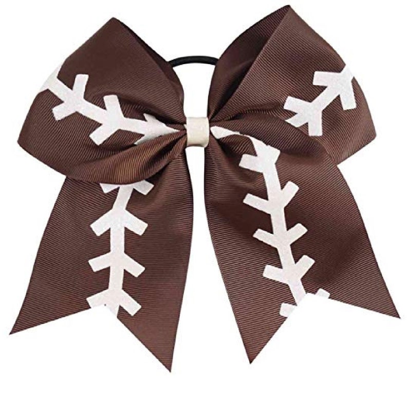 May include: A brown cheer bow with a white football stitch design. The bow is attached to a black elastic hair tie.