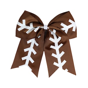 May include: A brown hair bow with a white football pattern. The bow is tied in a large, symmetrical shape.