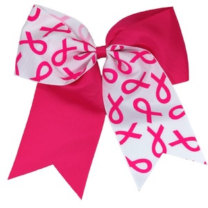 May include: A pink and white hair bow with a pink ribbon pattern. The bow is made of grosgrain ribbon and has a white center.