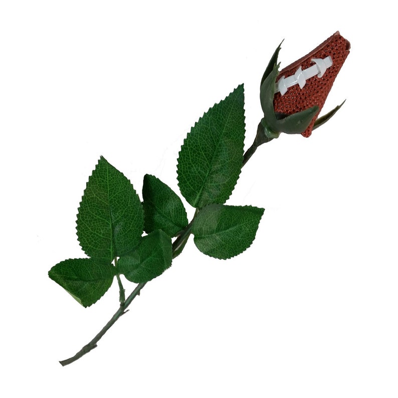 May include: A single artificial rose with green leaves. The rose bud is shaped like a football with white stitching.