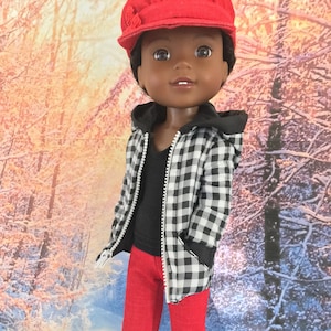 Peut inclure: Une poupée portant une veste en tissu écossais rouge et noir avec un sweat à capuche noir en dessous, un pantalon rouge et des baskets noires et blanches. La poupée porte une casquette de newsboy rouge avec un embellissement floral.