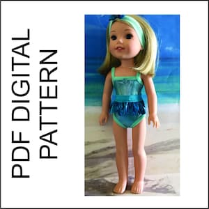 Può includere: Un costume da bagno turchese e blu con una gonna a balze per una bambola. La bambola indossa il costume da bagno e ha i capelli biondi con una fascia blu.