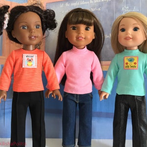 Peut inclure: Trois poupées portant des chemises à manches longues et des pantalons. La poupée à gauche porte une chemise orange avec un motif de hibou et un pantalon noir. La poupée du milieu porte une chemise rose et un jean bleu. La poupée à droite porte une chemise turquoise avec un motif d'oiseau et un pantalon noir.