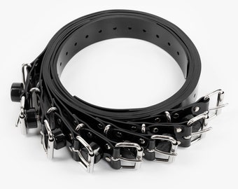 May include: A set of black rubber belts with silver buckles. The belts are rolled up and the buckles are visible.