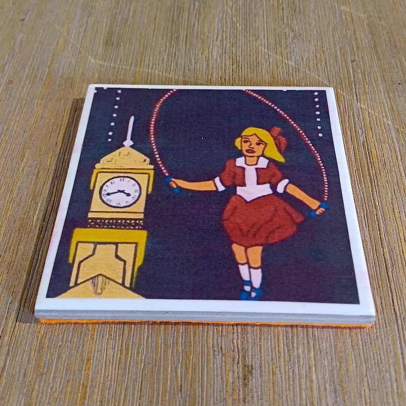 May include: A square ceramic tile featuring a graphic illustration of a person with blonde hair wearing a brown dress, jumping rope in front of a yellow clock tower against a dark purple background. The clock face shows black hands and markings.