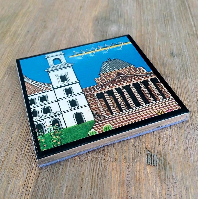 Puede incluir: Un posavasos cuadrado con una colorida ilustraci&oacute;n de una torre blanca y un edificio cl&aacute;sico con columnas. Sobre los edificios, se representa un bote de remos con varios remeros contra un cielo azul brillante. Borde de color negro.