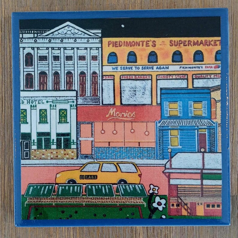 May include: A square ceramic tile featuring a colorful illustration of a city street scene. The image depicts a yellow taxi, a white hotel, and a yellow building labeled Piedmonte's Supermarket with text reading We Serve To Serve Again.