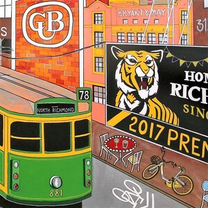 May include: A colorful painting depicting a green and yellow tram labeled North Richmond 78, passing a brick building with a GB logo, a Bryant & May sign, and a large billboard featuring a tiger illustration, the text 2017 PREM, a bicycle, and a cafe table.