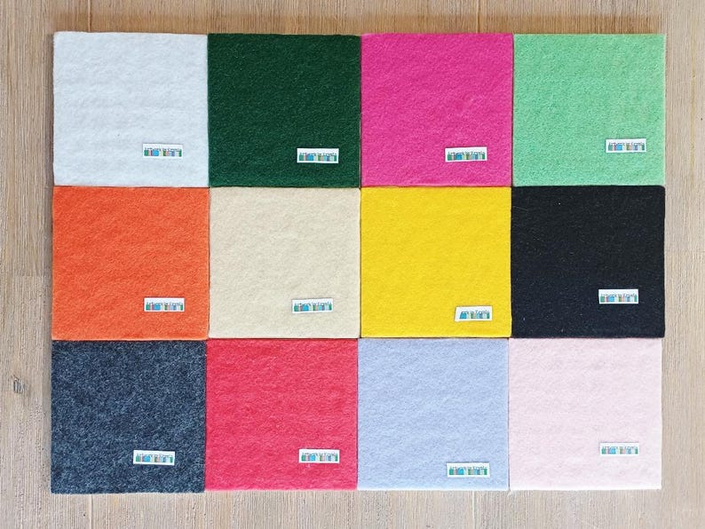 May include: A collection of twelve square felt sheets arranged in a grid, featuring a variety of colors including white, dark green, hot pink, light green, orange, cream, yellow, black, dark gray, red, light blue, and light pink.