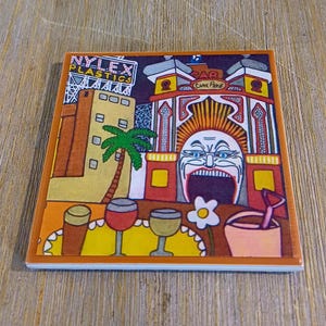 Puede incluir: Un posavasos cuadrado de cer&aacute;mica con una colorida ilustraci&oacute;n de la entrada del Luna Park con una cara grande, un letrero de Nylex Plastics, una palmera, tres vasos sobre una mesa amarilla, una flor blanca y un cubo rosa con una pala.