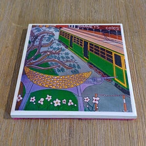 K&ouml;nnte beinhalten: Ein quadratischer Keramikuntersetzer mit einer farbenfrohen Illustration einer gr&uuml;nen und gelben Stra&szlig;enbahn. Der Text DIMMEYS... coles ist oben aufgedruckt. Die Szene zeigt stilisiertes violettes Blattwerk, eine gelbe gemusterte Mondsichel und wei&szlig;e Blumen.