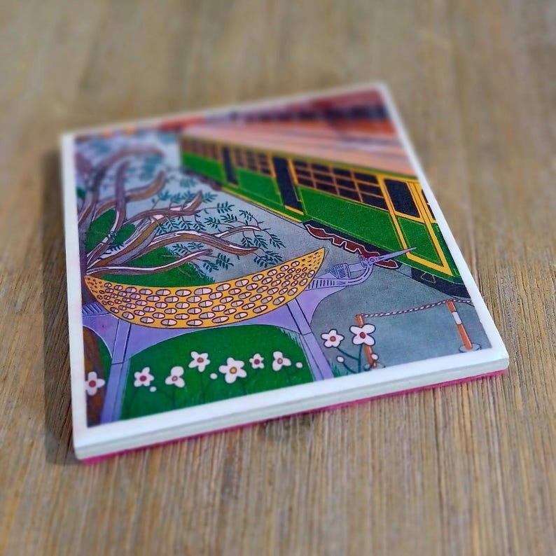 K&ouml;nnte beinhalten: Eine quadratische Keramikfliese mit einer farbenfrohen Illustration eines gr&uuml;nen und gelben Zugwagens, der neben einem stilisierten Baum und einer gelben gemusterten Struktur steht. Die Szene zeigt kleine wei&szlig;e Blumen auf gr&uuml;nem Grund.