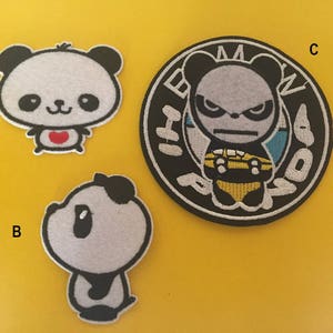 Pode incluir: Três patches bordados para passar a ferro com ursos panda. O primeiro patch é um panda branco com orelhas e olhos pretos, que segura um coração vermelho. O segundo patch é um panda branco com orelhas e olhos pretos. O terceiro patch é um panda branco e preto com um design amarelo e azul, que segura um objeto amarelo. O texto "BMW" está escrito em branco sobre um círculo preto em torno do panda.