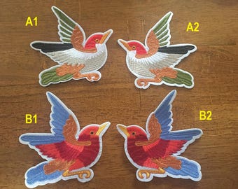 May include: Four embroidered iron-on patches of birds. Two birds are white with green, orange, and brown accents. The other two birds are red with blue, orange, and brown accents. The patches are labeled A1, A2, B1, and B2.