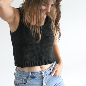 Puede incluir: Una mujer con un top corto de color verde oscuro y pantalones cortos de mezclilla azul claro.