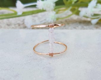 May include: A delicate gold ring with a row of clear beads hanging from the band.