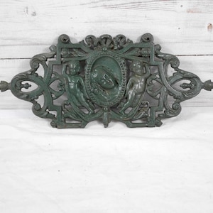 old cast iron plaque carved with cherub and woman's face