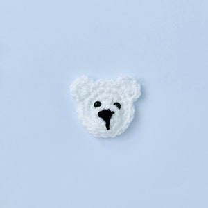 May include: White crocheted bear head with black eyes and nose.