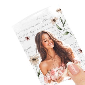 May include: A decorative sticker featuring a smiling woman with long brown hair, wearing a floral dress. The sticker has a vintage aesthetic with floral accents and handwritten script in the background.