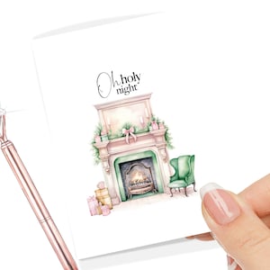 Puede incluir: Una ilustración de acuarela de una chimenea con fuego crepitante, un sillón verde y regalos envueltos en papel rosa y dorado. El texto "Oh holy night" está escrito sobre la chimenea.