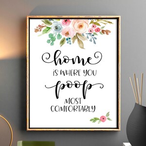 Könnte beinhalten: Ein weißer gerahmter Druck mit einem Blumendesign und dem Text "home is where you poop most comfortably".