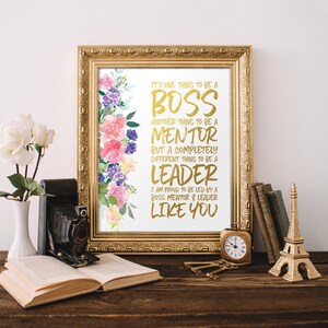 May include: A framed print with a watercolor floral design and gold text that reads "It's one thing to be a boss, another thing to be a mentor, but a completely different thing to be a leader. I am proud to be led by a boss, mentor & leader like you."