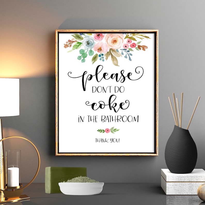 May include: A white sign with a floral design at the top and the text "Please don't do coke in the bathroom. Thank you!" in black lettering.