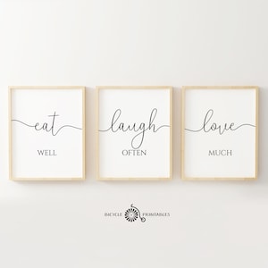 May include: Three framed prints with black calligraphy on a white background. The prints read "eat well", "laugh often", and "love much".