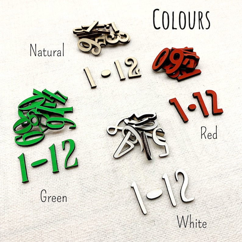 Pu&ograve; includere: Set di numeri in legno in vari colori, tra cui naturale, rosso, verde e bianco. L'immagine mostra singoli numeri e set da 1-12, con la parola "COLOURS" in alto e i nomi dei colori sotto.