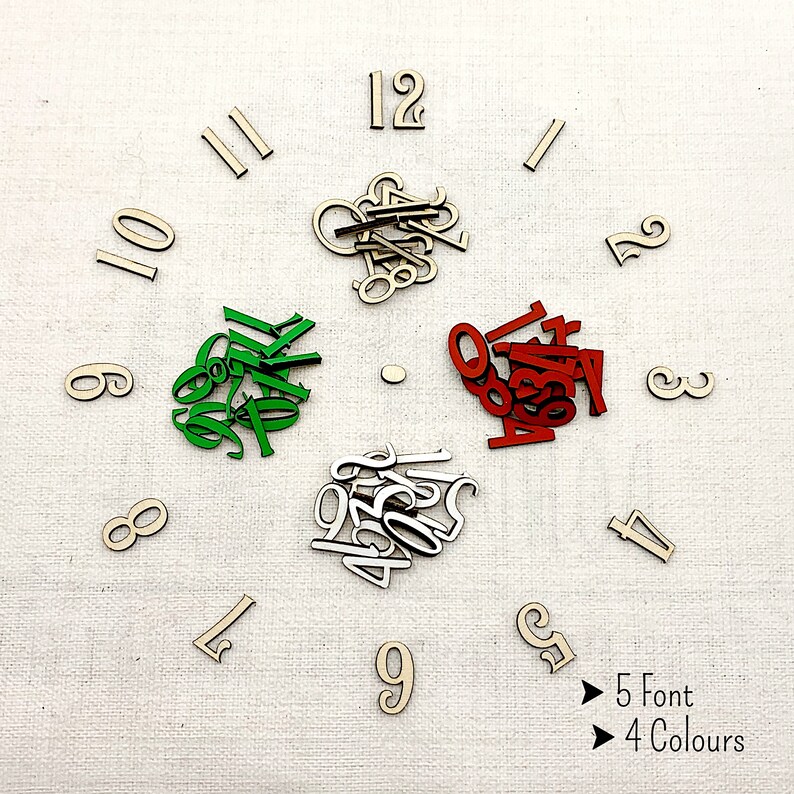 Pu&ograve; includere: Numeri di orologio in legno in cinque caratteri e quattro colori: legno naturale, verde, rosso e argento. I numeri sono disposti su una superficie bianca per assomigliare a un quadrante dell'orologio. Il testo nell'immagine recita "5 Font 4 Colours."