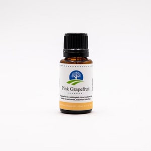 May include: A small amber glass bottle with a black cap, containing pink grapefruit essential oil. The label features a green tree and the text "Pink Grapefruit".