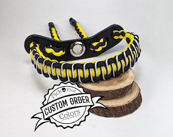 May include: A black and yellow archery wrist release aid with a leather base and a woven nylon strap. The wrist strap features a black, yellow, and white pattern. The image includes the text "Pick Your Custom Order Colors".