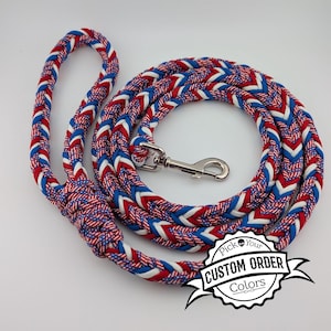 May include: Braided dog leash in red, white, and blue. The leash has a loop handle and a metal clasp. The leash is coiled on a white surface. The image includes a logo that says "Pick Your Custom Order Colors."