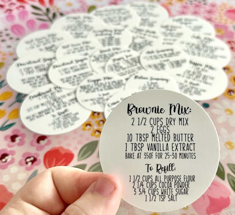 May include: White round sticker with black text that reads "Brownie Mix: 2 1/2 cups dry mix, 2 eggs, 10 tbsp melted butter, 1 tbsp vanilla extract, bake at 350F for 25-30 minutes. To Refill: 1 1/2 cups all purpose flour, 2 1/4 cups cocoa powder, 3 3/4 cups white sugar, 1 1/2 tsp salt."