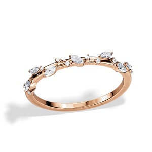 May include: Rose gold ring featuring a delicate design of marquise and round-cut diamonds. The ring's band is a smooth, polished rose gold, with the diamonds arranged in a subtle, organic pattern across the top.