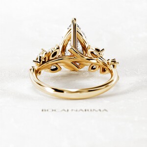 Puede incluir: Un anillo de compromiso de oro en forma de pera con un delicado dise&ntilde;o floral. El anillo presenta una piedra central en forma de pera y piedras redondas m&aacute;s peque&ntilde;as engastadas en el dise&ntilde;o floral.