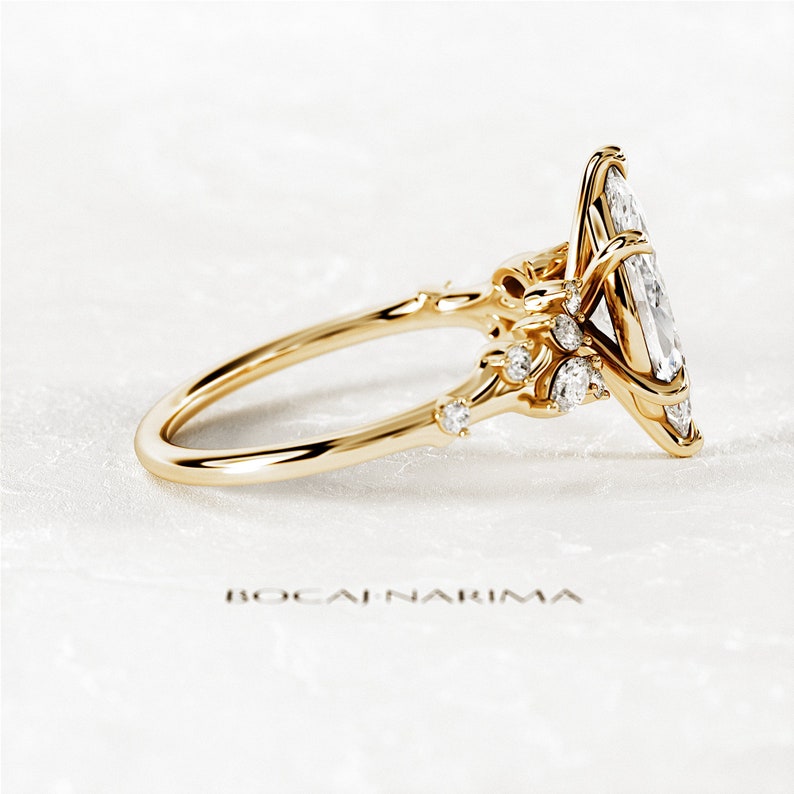 May include: A gold engagement ring with a large oval-shaped diamond set in a delicate, intricate design. Smaller diamonds are set along the band and on the sides of the main stone.