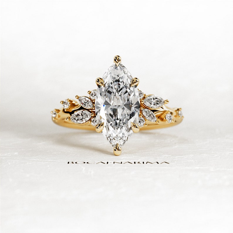 May include: A gold engagement ring with a large marquise-shaped diamond surrounded by smaller diamonds. The ring has a delicate floral design.