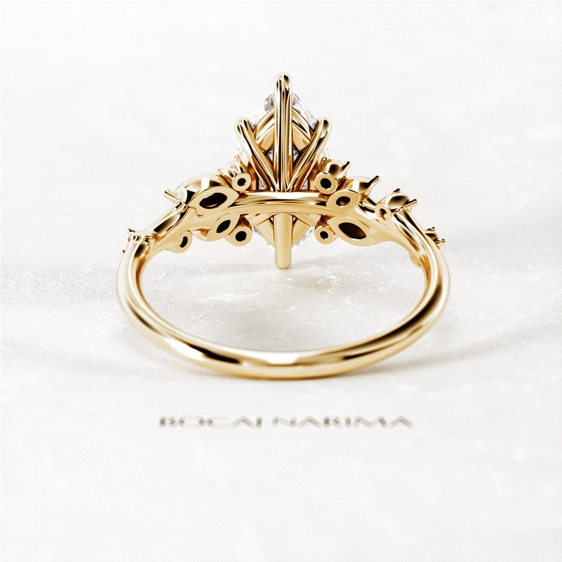 May include: A gold engagement ring with a marquise-shaped diamond center stone and smaller diamonds set in a floral design on the band.