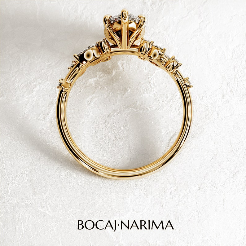 May include: A gold ring with a large, round, clear gemstone in the center. The ring has a delicate, floral design with smaller gemstones on the band.