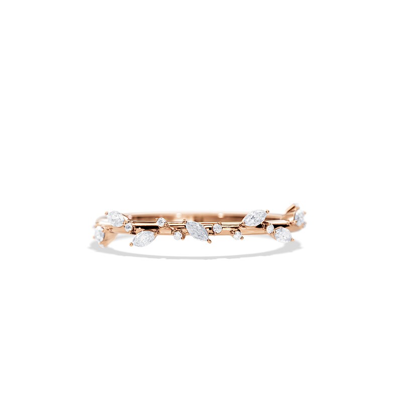 May include: Rose gold ring featuring a delicate vine design. The ring is adorned with marquise-cut and round-cut white gemstones, creating a nature-inspired aesthetic. The band has a polished finish, enhancing the ring's overall elegance.