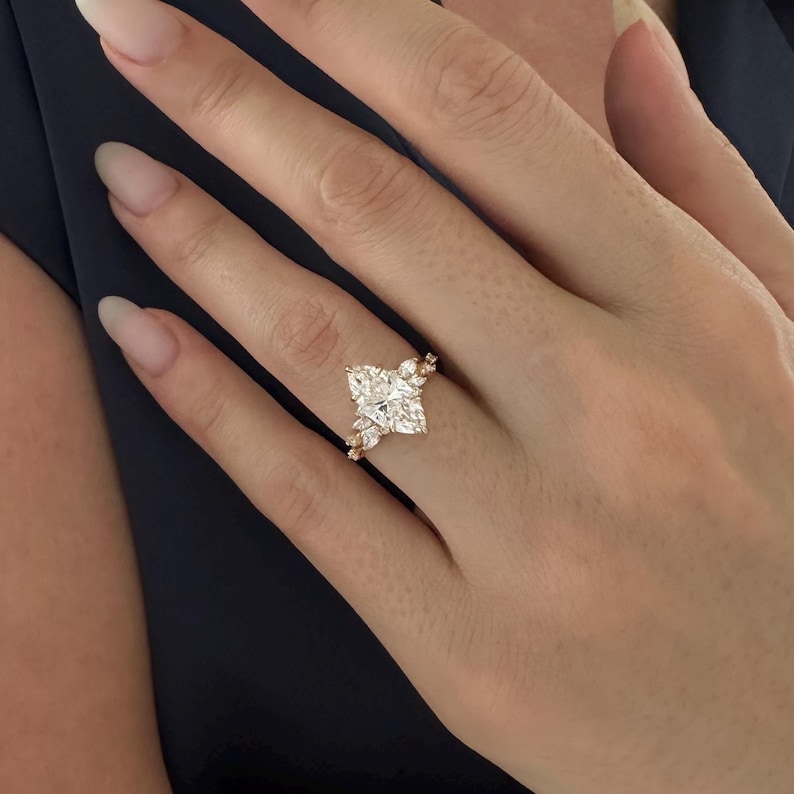 May include: A gold engagement ring with a large, clear, marquise-shaped diamond surrounded by smaller diamonds.
