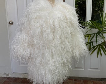 May include: A white feather boa jacket on a mannequin. The jacket is fluffy and has a long, flowing design.
