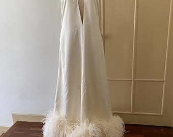 May include: A white halter dress with a keyhole neckline and a feather trim at the hem.