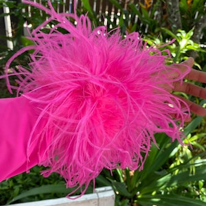 May include: A bright pink fluffy feather trim for clothing. The trim is made of soft, delicate feathers and is perfect for adding a touch of whimsy to any garment.