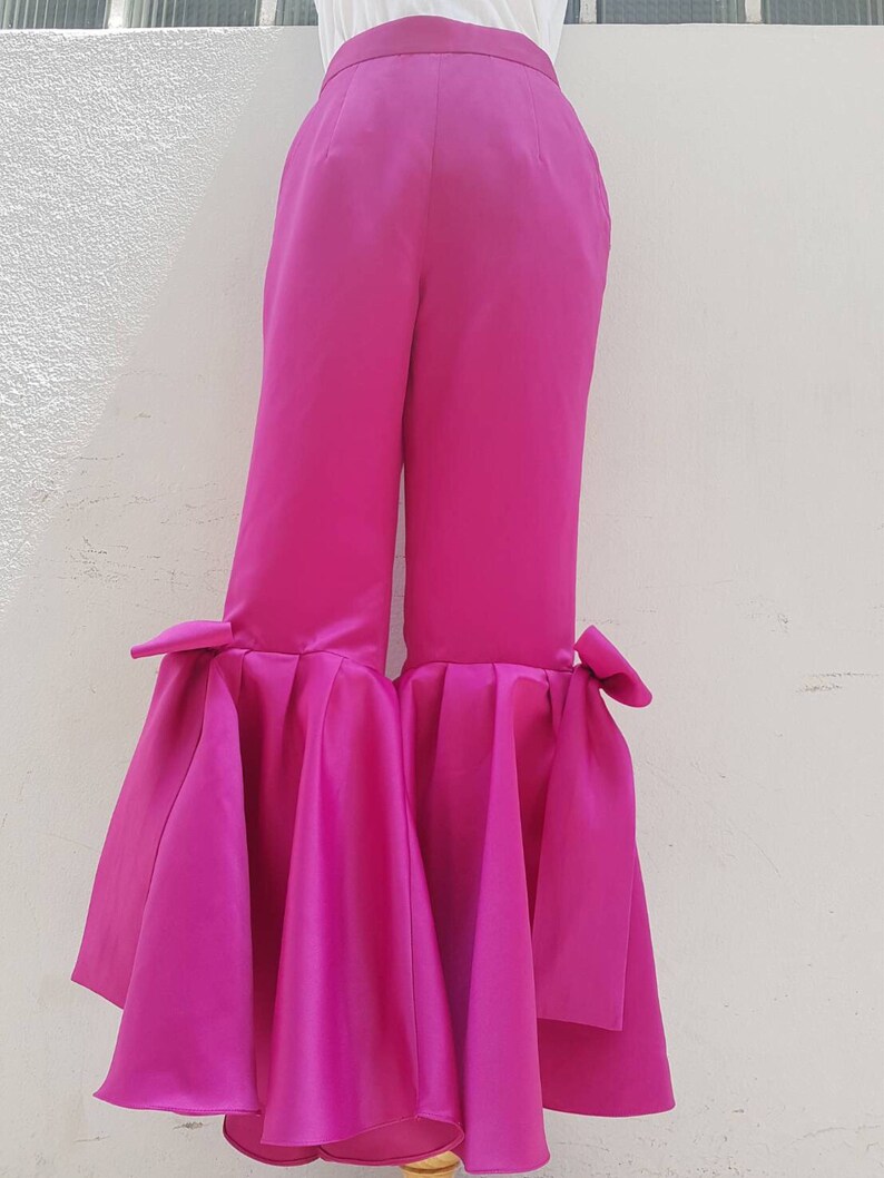 Peut inclure: Pantalon large fuchsia &agrave; jambes larges avec un ourlet &agrave; volants et des d&eacute;tails en n&oelig;ud au bas de chaque jambe.
